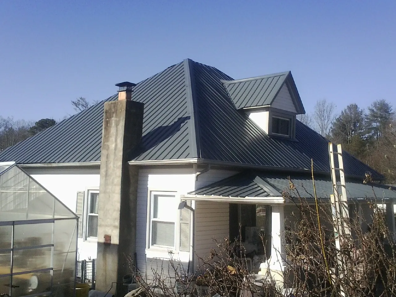Dark blue standing seam metal roof on a white farmhouse with dormer — Slate & Tile Roof Repair by Roofing Brothers in Hyde Park